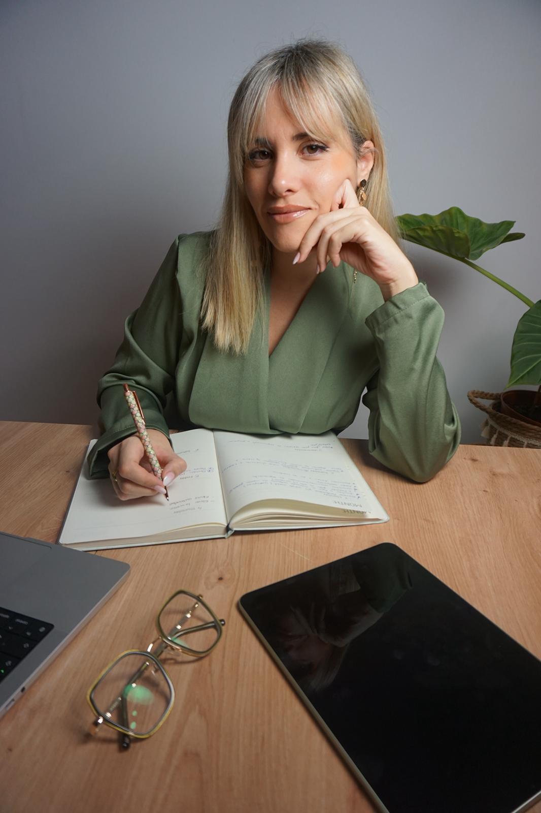 Gemma Ojeda escribiendo en su cuaderno junto al portátil